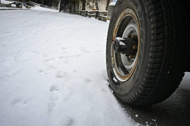 Vehicle tire and wheel parked on a snow-covered road during cold winter weather