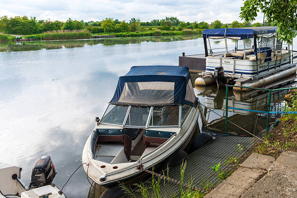 Tyniec Abbey, Poland – May 23, 2025: Quiet marina corner with a motorboat tied beside a metal ramp and floating platform. Still water reflections and soft light create a relaxed scene for boating, travel, and leisure concepts.