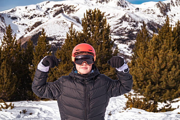 Young person wearing ski gear flexing biceps, showing strength and confidence in winter mountains