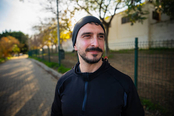 Man with beard and mustache wearing black sportswear looking away during a fitness activity