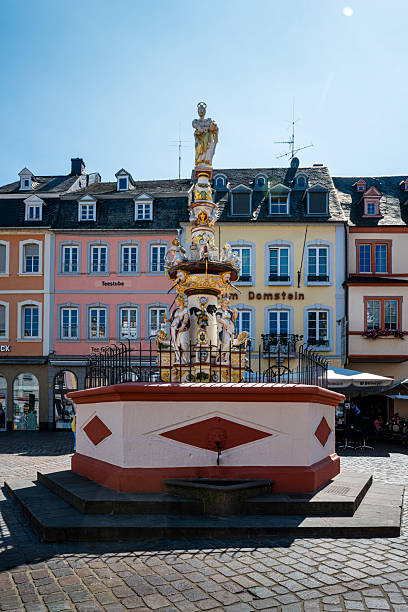 Trier, Deutschland - 10. August 2025: Fountain at Main Market Square with many restaurants and pubs at beautiful weather