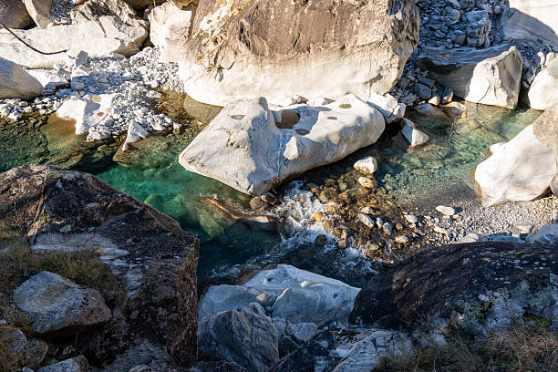 A close-up of the rapids of a mountain river that flows down among the rocks, a front view of a stepped riverbed.