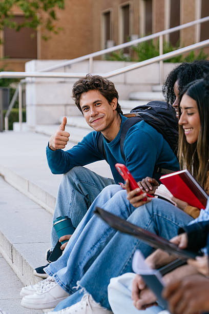 istock Multiracial students sitting on campus stairs giving thumbs up 2256293414