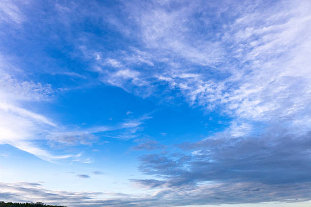 The sky is a vibrant blue, with soft white clouds drifting gently. Some clouds are thin and wispy, while others are thick and fluffy, creating a peaceful look.