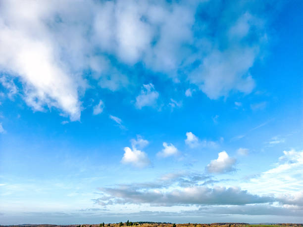 The sky is a vibrant blue, with soft white clouds drifting gently. Some clouds are thin and wispy, while others are thick and fluffy, creating a peaceful look.