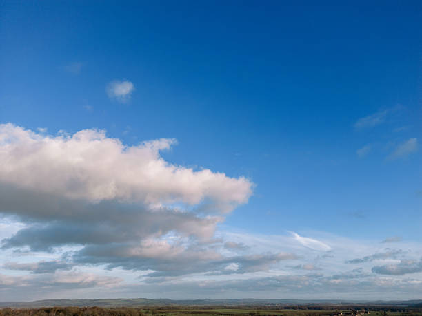 The sky is a vibrant blue, with soft white clouds drifting gently. Some clouds are thin and wispy, while others are thick and fluffy, creating a peaceful look.