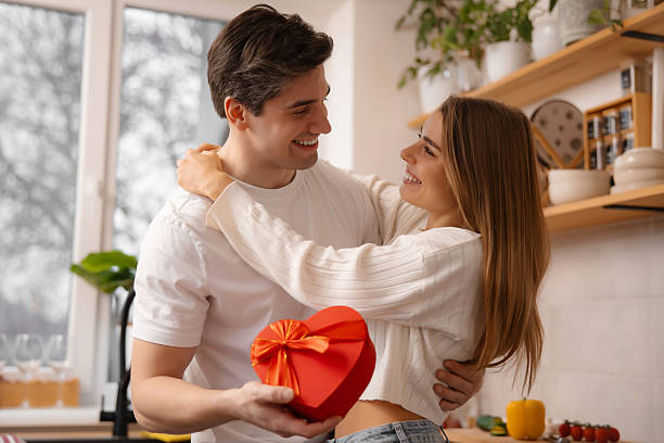 istock Romantic Man Surprising Woman with Heart Box in Kitchen 2256296104