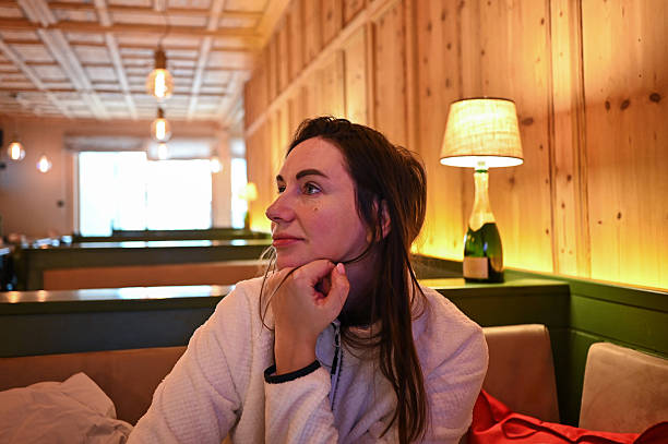 Woman looking away, lost in thought inside a restaurant booth with warm ambiance