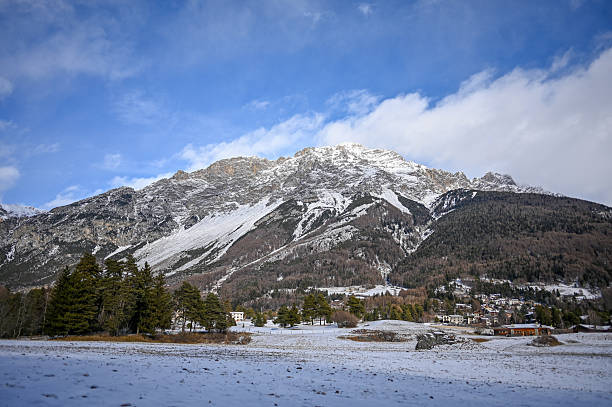 Snow-covered landscape with pine trees and buildings in a mountain valley