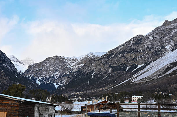 Village and rustic buildings resting in a snowy Alpine valley with towering mountains