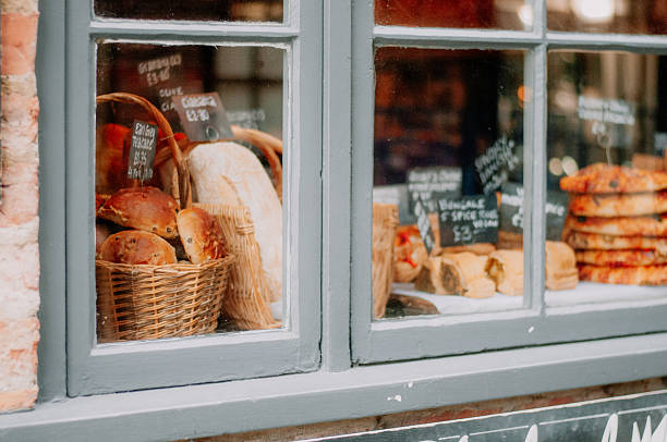A old bike leaning against a building with round loaves of bread in the window.