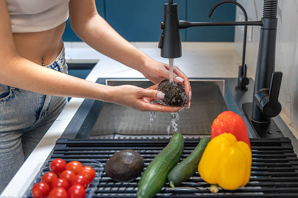 Woman washes avocado close up in kitchen. Clean hands.