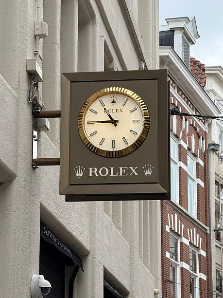 den haag, netherlands July 28 2025: A Rolex clock showing the time mounted on a wall of a store in a city with classic architecture on a cloudy day.