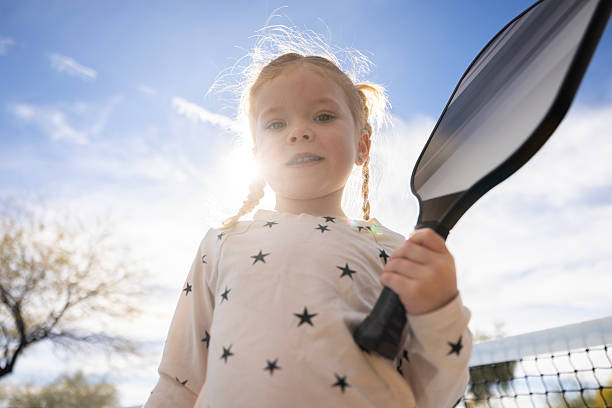 A four year old girl playing pickleball at the park