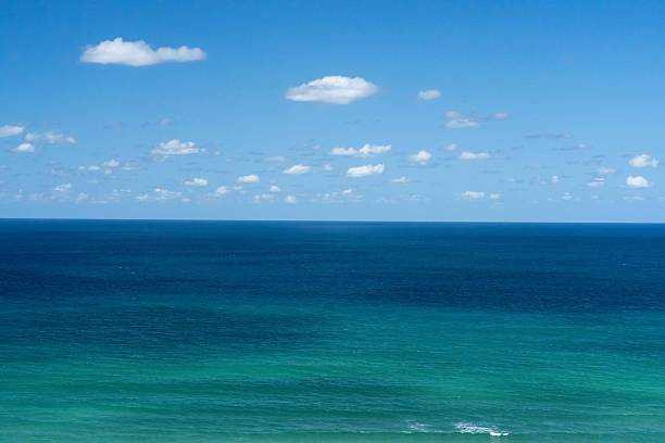 This elevated coastal view looks down over a lush white sand beach and turquoise water, capturing the clarity, openness, and natural beauty of a perfect tropical day
