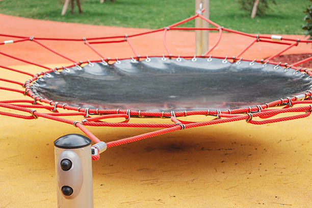 Modern round trampoline for kids integrated into a colorful children's playground surface, providing fun and active recreation