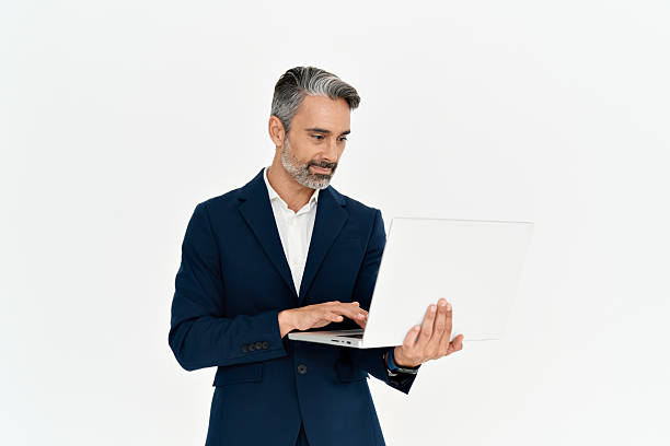 istock Busy mature business man using laptop standing isolated on white background. 2256328622