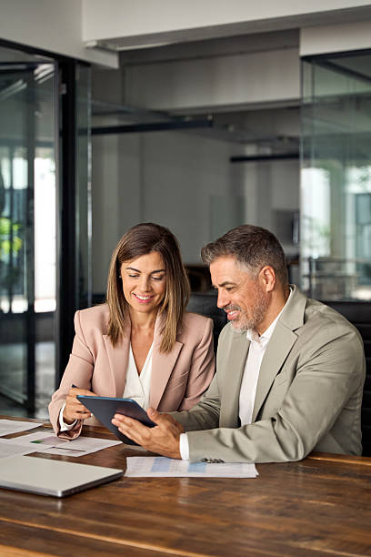 istock Two executive managers working on digital tablet at meeting in office. Vertical 2256328816