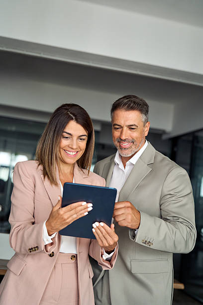 istock Smiling business executives discuss digital strategy using tablet in office. 2256328869