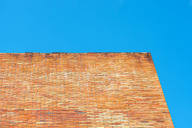 Textured background of red brick wall against a sunny blue sky