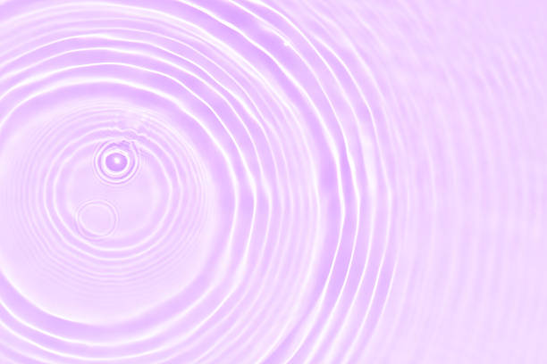 Pink water bubbles on the surface ripples. Defocus blurred transparent pink colored clear calm water surface texture with splash and bubbles. Water waves with shining pattern texture background