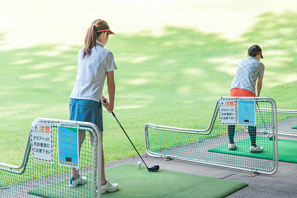 Male and female golfers practicing their swing at a golf driving range or golf center