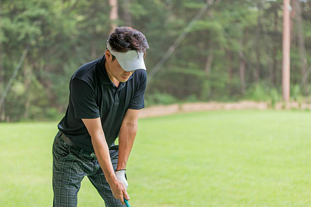 Young Caucasian female golfer placing a golf ball on the tee box, preparing for her drive with focused determination on a sunny day at the golf course.