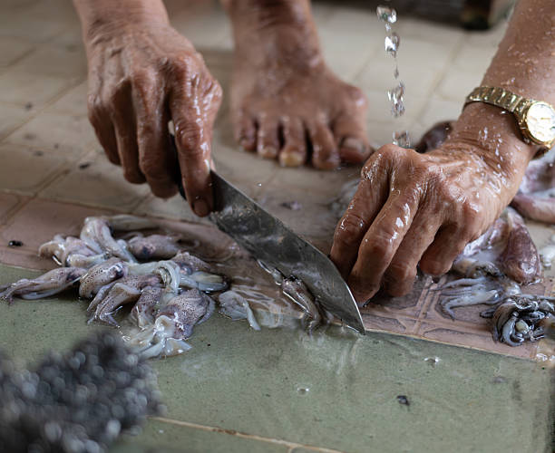 Manual seafood processing in a traditional Asian kitchen environment showing local lifestyle.