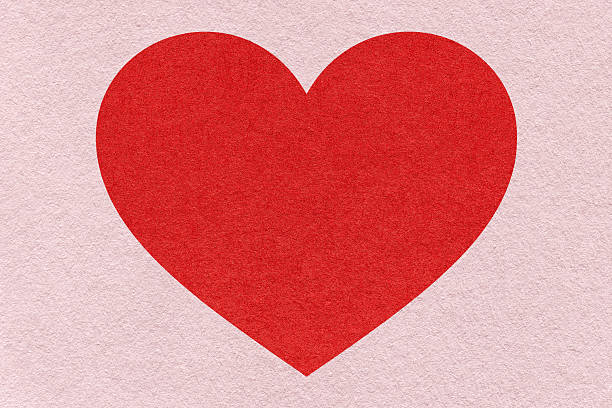 Red heart on light pink paper texture background with copy space for Valentines Day banner, template or greeting card.