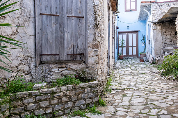 Traditional cobblestone alley winding between weathered stone walls and buildings, showcasing historic lania village architecture