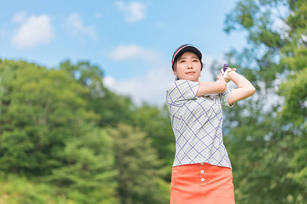 Focused of Thai young woman hitting shot while playing golf at golf course,Golfer making the chip. Women in sports. Focus and determination concepts.