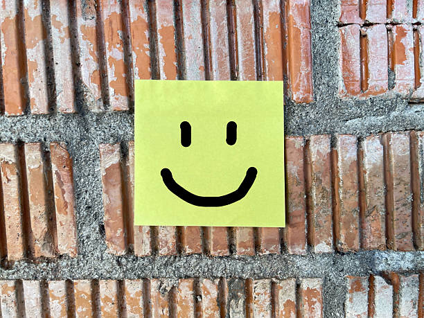 Smiley face note attached to brick wall.