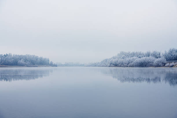 Late autumn landscape on the river. River, trees and plants covered with frost