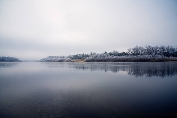 Late autumn landscape on the river. River, trees and plants covered with frost