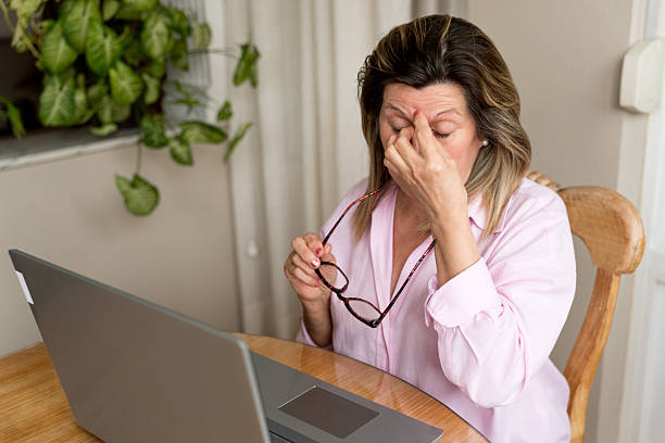 istock Middle-aged woman experiencing a headache and eye fatigue, holding her glasses while working on a laptop remotely 2256401753