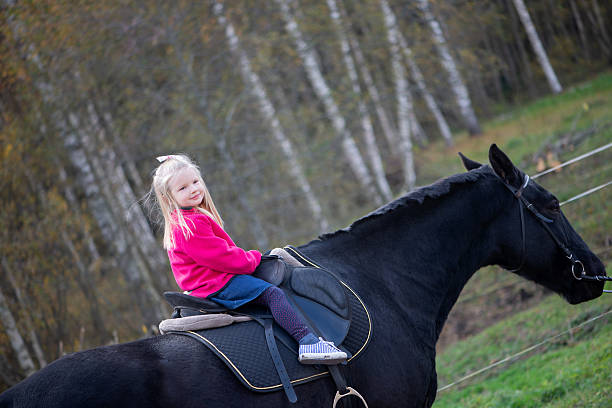 Portrait of a child girl with down syndrome horseback riding outdoors