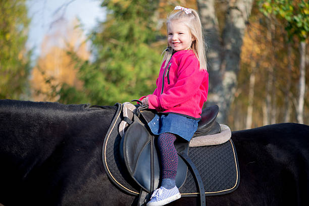 Portrait of a child girl with down syndrome horseback riding outdoors