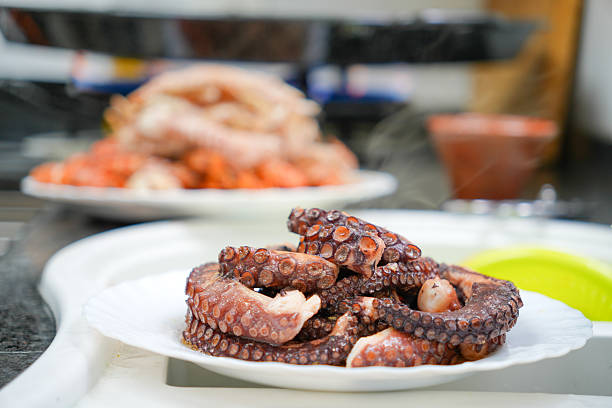 A plate of octopus is on a table. The plate is white and the octopus is brown