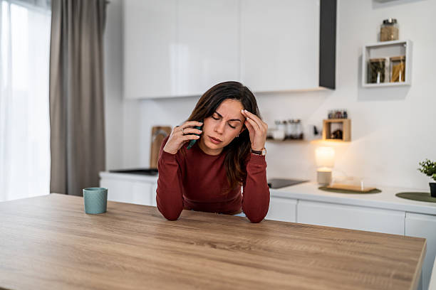 istock Woman experiencing headache stress talking on phone at home 2256405814