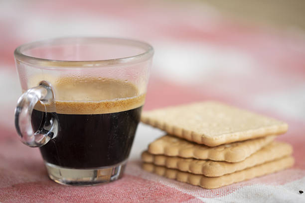 glass cup of creamy espresso  and stack of biscuits on pastel pink surface cozy morning coffee break and snack time aesthetic