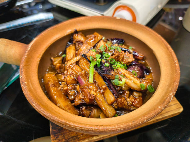 A warm and inviting clay pot filled with a savory stew featuring eggplant and pork, encapsulating rich flavors and traditions, presenting a hearty homemade meal that evokes nostalgia.