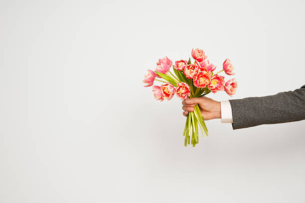 Romantic man presents a bouquet of tulips on an isolated white background, Valentine's Day, March 8