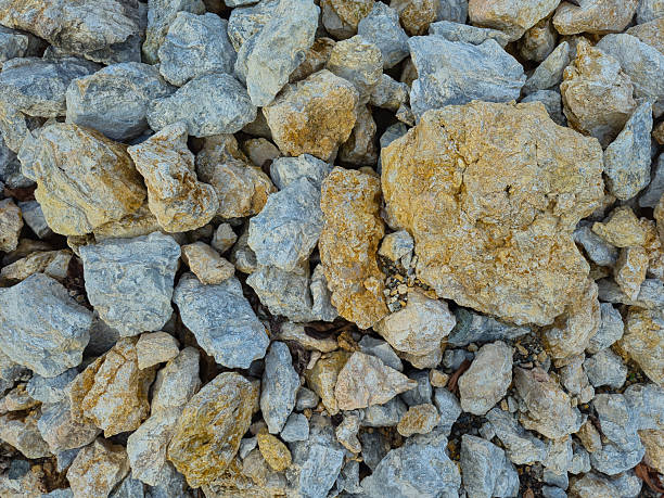 Top view of crushed limestone and gravel. Textured gray and yellow stones for construction, road base, and landscaping projects. Natural mineral aggregate background