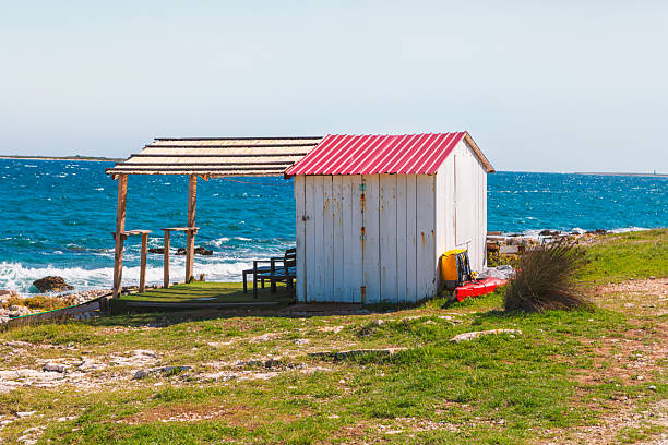 Rustic wooden cabins under construction, painted in striking blue and red hues, set against a dramatic landscape at dusk. A blend of craftsmanship and nature's beauty