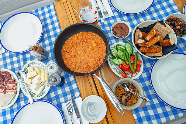 Traditional Turkish breakfast spread on wooden table with blue checkered tablecloth and assorted dishes in restaurant setting