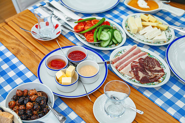 Traditional Turkish breakfast spread on wooden table with blue checkered tablecloth and assorted dishes in restaurant setting