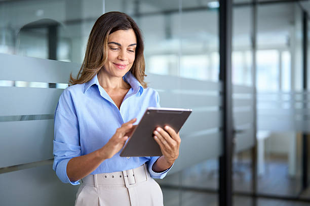 istock Smiling mature professional business woman using tablet standing in office. 2256422546