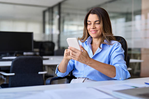 istock Smiling mature business woman executive using cell phone working in office. 2256422634