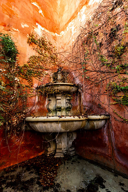 A charming two tiered fountain with lush ivy decorates a vibrant corner of a building in Seville, reflecting rustic Spanish beauty.