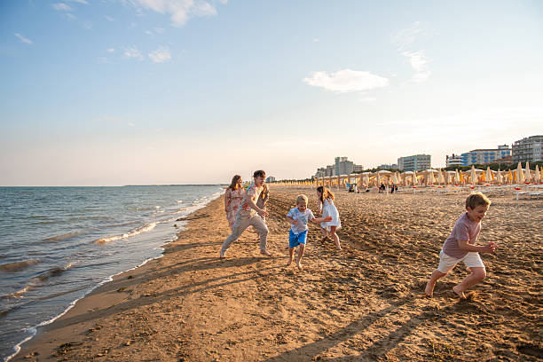 Children Racing Along Sandy Beach with Two Mothers